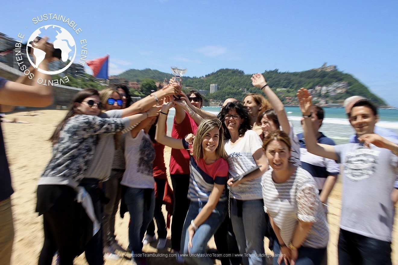 A happy team celebrating victory on La Concha Beach with Mount Igueldo and the blue sea in the background in San Sebastián.