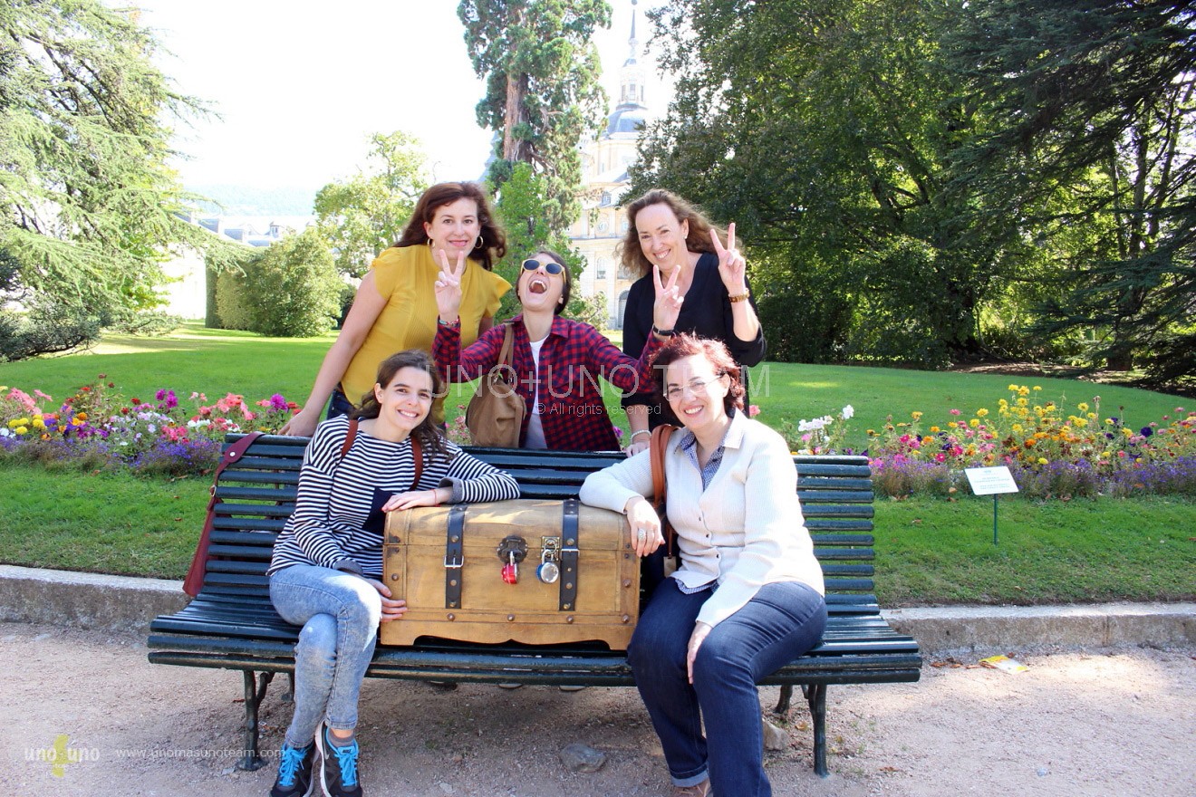 Five team members celebrating the treasure discovery beside a majestic cedar tree in front of the Royal Palace of La Granja de San Ildefonso.