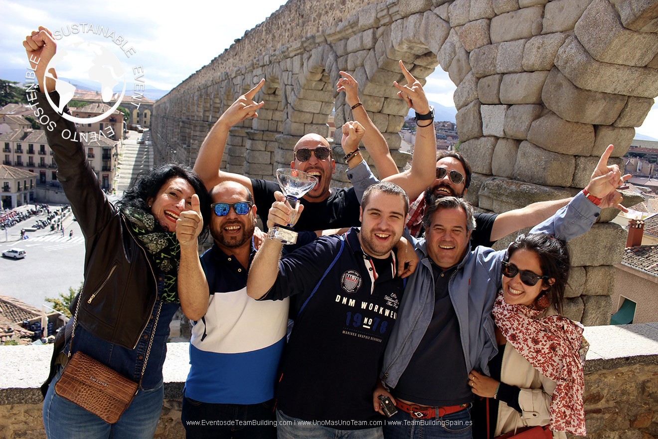 Corporate team joyfully celebrating victory at the upper viewpoint of the Segovia Aqueduct in autumn during En Busca del Tesoro.